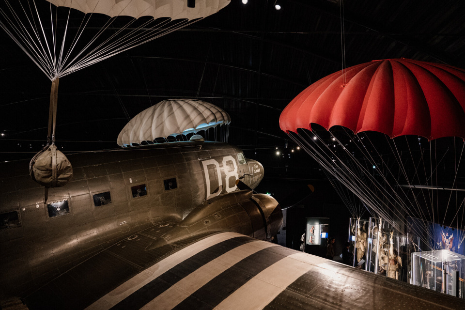 airborne-museum-c47-marie-anais-thierry Intérieur de l’Airborne Museum avec un avion C-47 et parachutes.