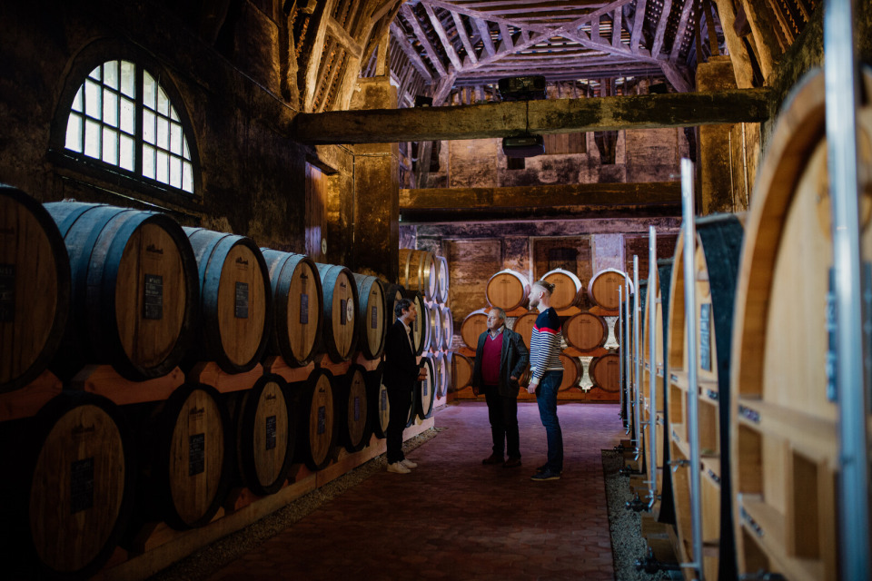 chateau-du-breuil-calvados-marie-anais-thierry Atelier Calvados au Château du Breuil, Pays d’Auge, avec des visiteurs dans une cave remplie de tonneaux.