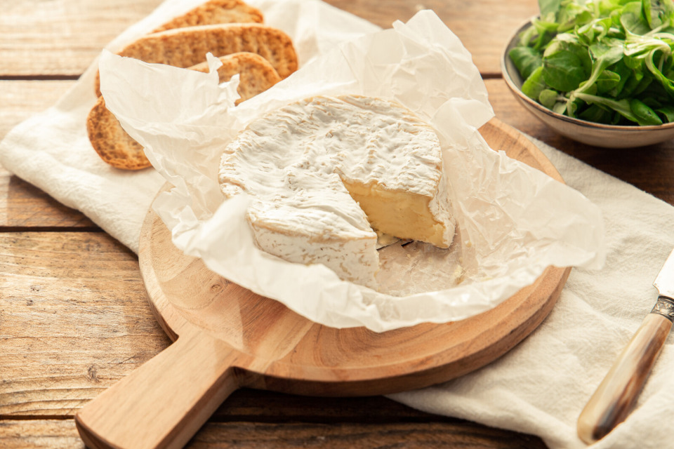 fromage-camembert-normand-credit-mathilde-boclet Camembert normand sur une planche en bois avec du pain.