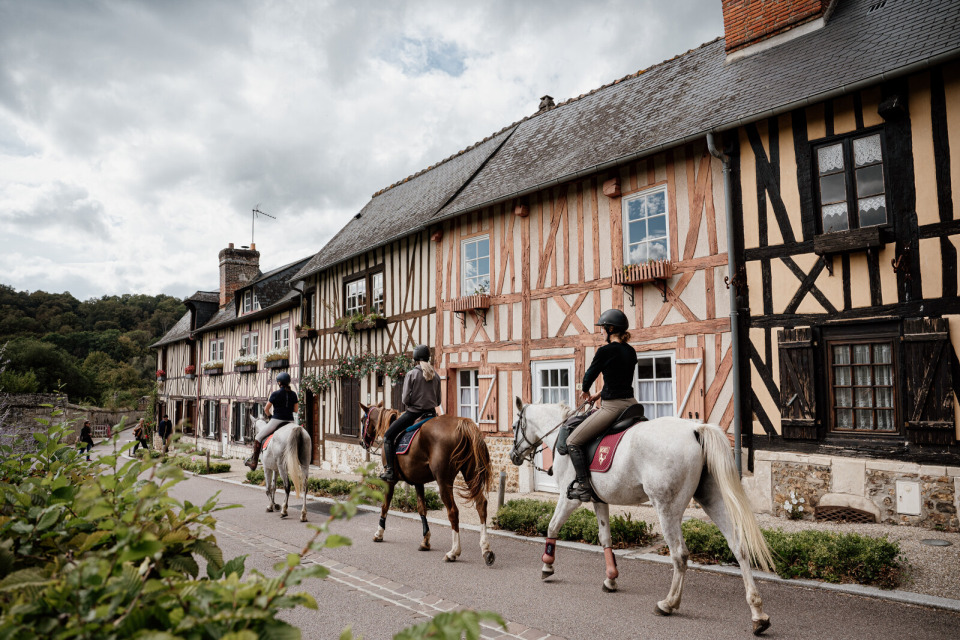 le-bec-hellouin-marie-anais-thierry Cavaliers découvrant les rues pittoresques du Bec-Hellouin, avec ses maisons à colombages typiques.
