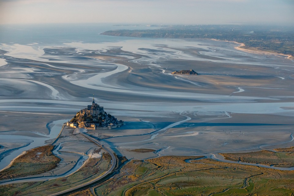 mont-saint-michel-baie-valentin-pacaut Vue aérienne du Mont-Saint-Michel entouré de sa baie à marée basse.