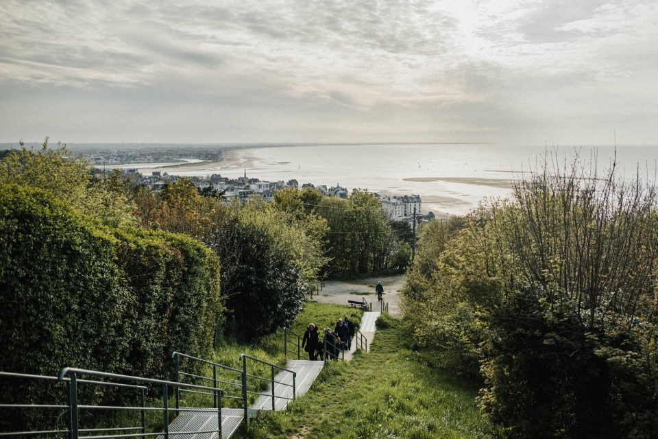 Vue en hauteur sur la plage et les toits de Houlgate avec la mer à l’horizon.