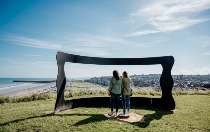 Deux personnes admirant Dieppe à travers une sculpture en forme de cadre