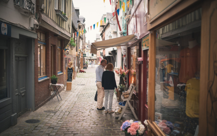 Rue commerçante pittoresque de Pont-Audemer, avec des boutiques et des passants.